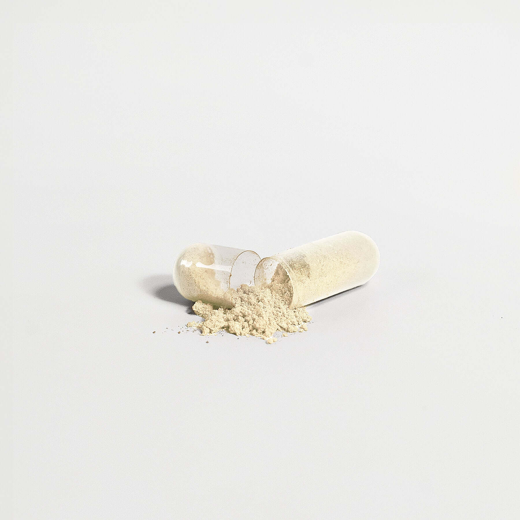 Close-up image of an open NaturaVivo Gut Health capsule with natural beige powder spilled on a white surface.