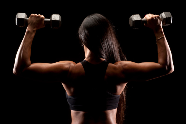 a young woman lifting two dumbbells during workout