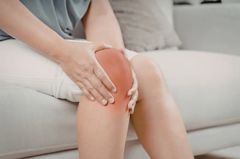 Person experiencing knee pain while sitting on sofa